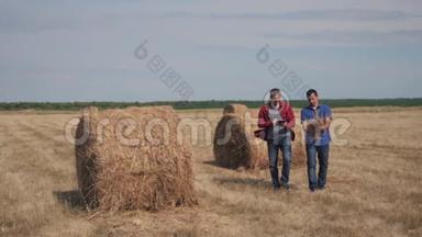 团队农业智慧农业理念.. 两名男子农民在数字平板电脑上研究干草堆